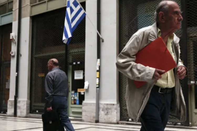 
	Pessoas passam por bandeira da Gr&eacute;cia em rua do centro de Atenas: n&uacute;mero de desempregados atingiu 1,38 milh&atilde;o de pessoas
 (REUTERS/Yorgos Karahalis)