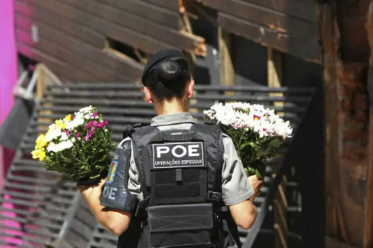 
	Policial carrega flores em frente &agrave; boate Kiss, onde um inc&ecirc;ndio matou 234 pessoas na cidade de Santa Maria
 (REUTERS/Edison Vara)