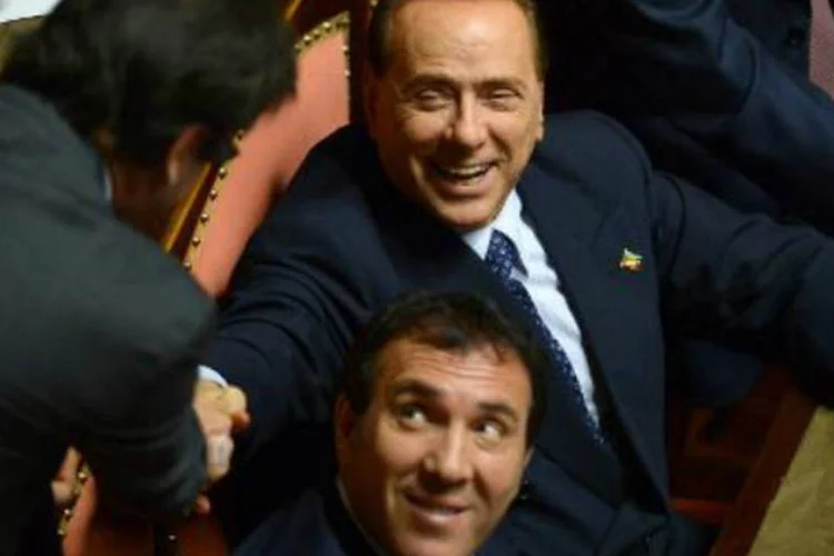 
	Silvio Berlusconi: ex-primeiro-ministro e l&iacute;der da direita da It&aacute;lia, &eacute; parabenizado por um senador ap&oacute;s o seu voto, no Congresso do pa&iacute;s, em Roma
 (AFP)