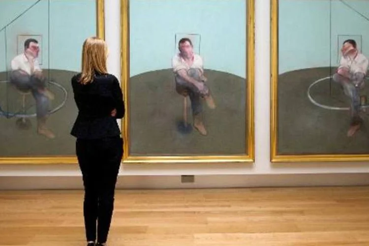 Funcionária da casa de leilão Christie's admira "Three Studies for a Portrait of John Edwards", tríptico de Francis Bacon, durante sessão de fotos em Londres, em 11 de abril de 2014 (Andrew Cowie/AFP)