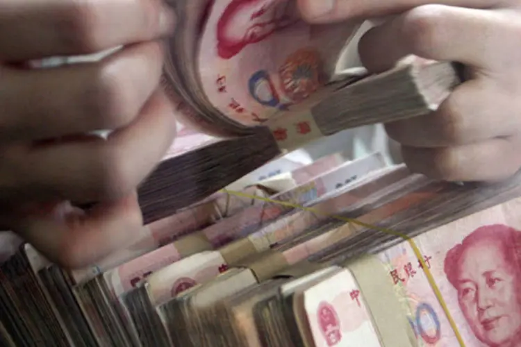 
	Caixa de banco conta notas de 100 yuan (ou Renminbi) na China: os empr&eacute;stimos vencidos em bancos comerciais ao fim de junho somaram 1,09 trilh&atilde;o de iuanes
 (China Photos/Getty Images)