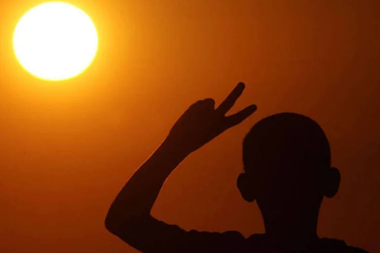 Menino faz símbolo da paz diante do sol (Abid Katib/Getty Images)