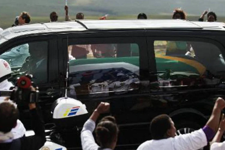 
	Sul-africanos acenam para o carro que transporta o caix&atilde;o de Nelson Mandela no caminho para Qunu: em 1994, ap&oacute;s d&eacute;cadas do apartheid, os negros puderam votar pela primeira vez
 (Gianluigi Guercia/AFP)