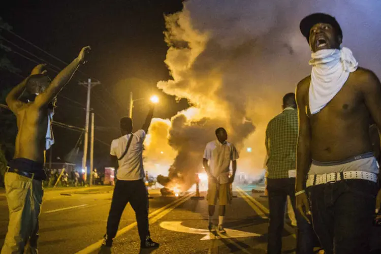 
	Manifestantes em meio ao g&aacute;s lacrimog&eacute;neo disparado pela pol&iacute;cia, em Ferguson, Missouri
 (REUTERS/Lucas Jackson)