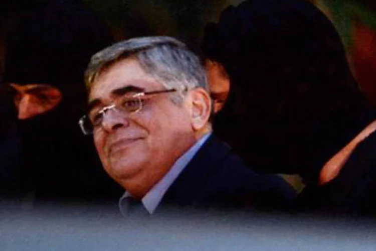 O líder do partido neonazista Aurora Dourada, Nikos Michaloliakos, levado por policiais para tribunal de Atenas em 2 de outubro
 (ARIS MESSINIS/AFP)