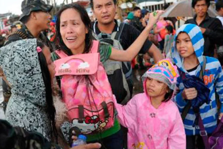 Família desabrigada em Tacloban não consegue embarcar em voo para deixar a cidade devastada pelo tufão Haiyan
 (TED ALJIBE/AFP)