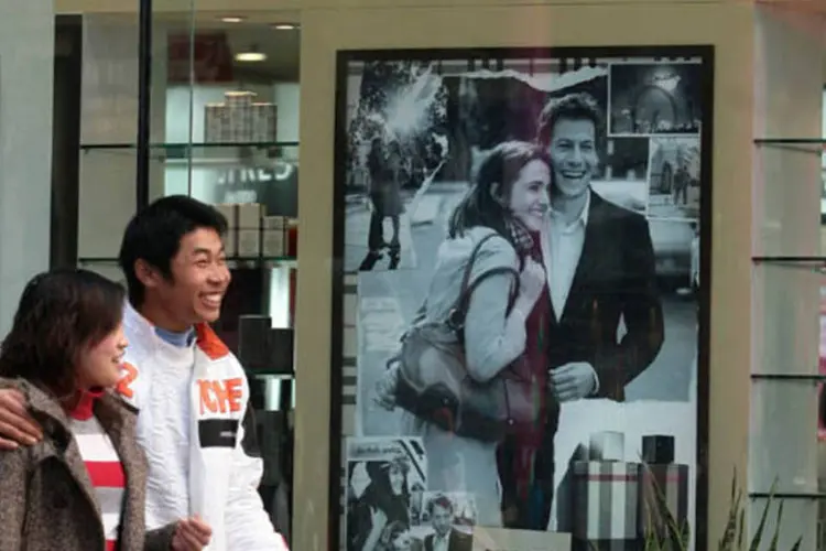 
	Casal passa na frente de uma loja da companhia brit&acirc;nica Burberry em Nanjing, na China: segundo o China Securities Journal, estas mudan&ccedil;as v&atilde;o ajudar a tornar a economia mais vibrante
 (China Photos/Getty Images)