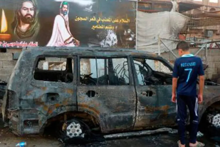 
	Garoto observa carro queimado em atentado em Bagd&aacute;: a pol&iacute;cia acredita que o n&uacute;mero de v&iacute;timas fatais possa aumentar&nbsp;
 (Ali al-Saadi/AFP)