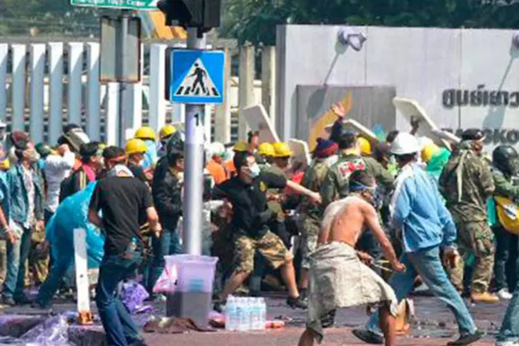 
	Manifestantes anti-governo enfrentam policiais durante protesto na Tail&acirc;ndia: pelo menos outros dois policiais e um membro dos servi&ccedil;os m&eacute;dicos ficaram feridos por armas de fogo
 (Pornchai Kittiwongsakul/AFP)