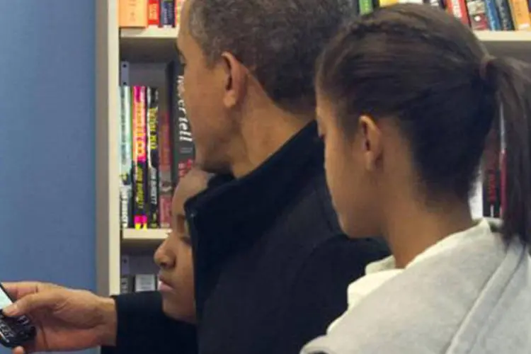 Barack Obama usa seu telefone Blackberry ao lado das filhas Sasha e Malia, em 24 de novembro de 2012 (Saul Loeb/AFP)