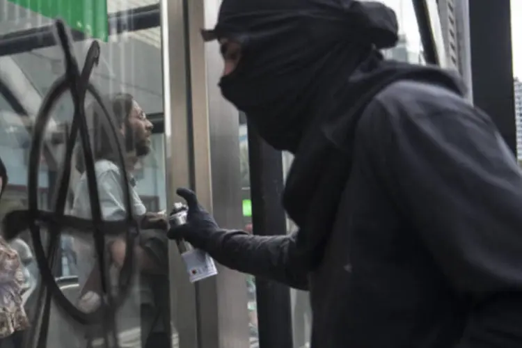 
	Manifestante do Black Bloc picha muro com o s&iacute;mbolo anarquista durante protesto
 (Marcelo Camargo/ABr)