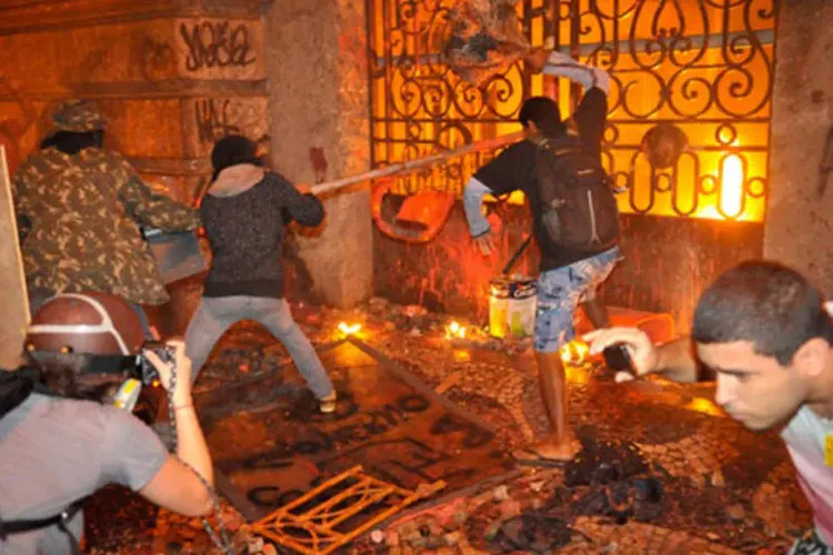 
	Manifestantes tentam destruir port&atilde;o da C&acirc;mara de Vereadores durante protesto no Rio, nesta semana: somando tudo, preju&iacute;zo pode ter passado de R$ 1 bilh&atilde;o
 (Fernando Frazão/ABr)