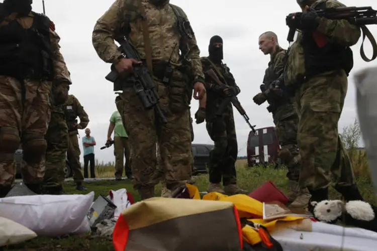 Separatistas pró-Rússia olham os pertences das vítimas do acidente aéreo da Malaysia Airlines (Maxim Zmeyev/Reuters)