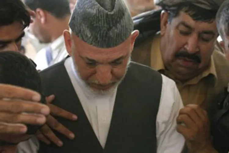 O presidente Hamid Karzai (ao centro), que chorou durante toda a cerimônia, foi consolado por amigos e parentes, mas se recusou a deixar o local
 (Mamoon Durrani/AFP)