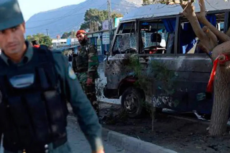 Soldados afegãos e policiais observam ônibus militar atingido por atentado em Cabul
 (Wakil Kohsar/AFP)