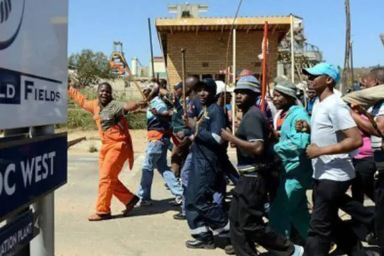 
	Mineradores em greve fazem uma passeata em Carletonville: os grevistas reivindicam um sal&aacute;rio de 2.900 reais mensais
 (AFP)