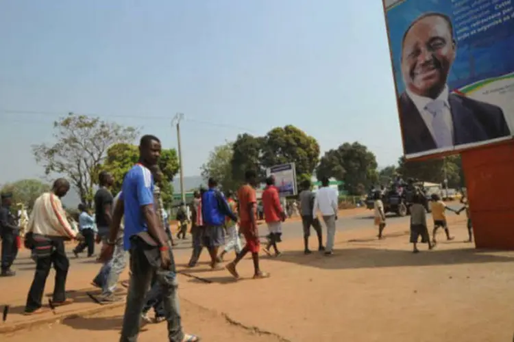 Moradores de Bangui passam por cartaz do presidente da República Centro-Africana, François Bozizé (©afp.com / Sia Kambou)