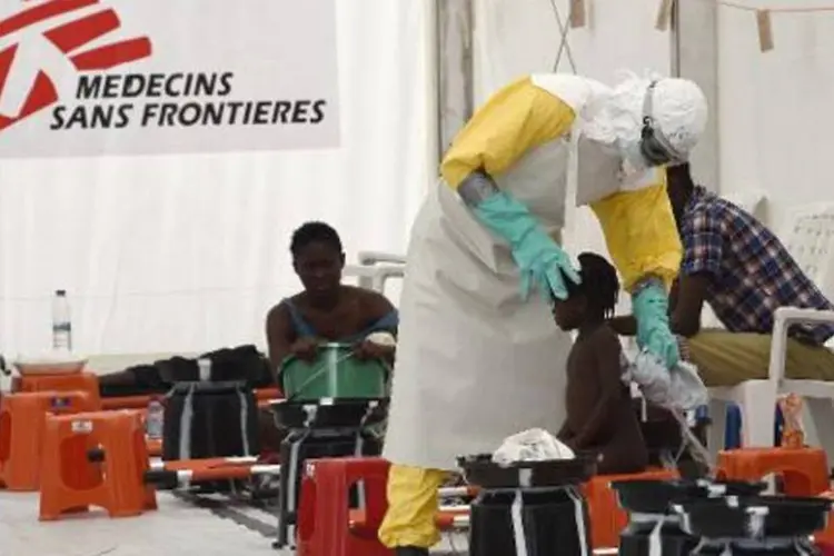 
	Agente de sa&uacute;de atende uma menina no centro de tratamento para pacientes de ebola na Lib&eacute;ria
 (Pascal Guyot/AFP)