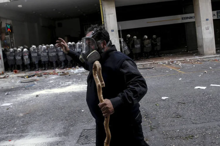 
	Agricultor grego protesta com cajado na m&atilde;o: os manifestantes atiraram pedras, quebrando janelas do edif&iacute;cio, e queimaram sacos com lixo
 (Alkis Konstantinidis/ Reuters)