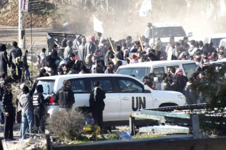 Civis se reúnem antes de uma evacuação com a ajuda do Crescente Vermelho e nas Nações Unidas na área sitiada de Homs, na Síria (Yazan Homsy/Reuters)