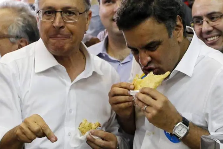 Geraldo Alckmin e Aécio Neves, ambos do PSDB, comendo pastel durante um ato político em Santos (Paulo Whitaker/Reuters)