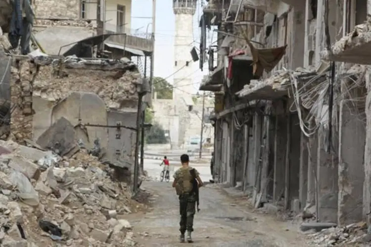 
	Combatente do Ex&eacute;rcito S&iacute;rio Livre passa por pr&eacute;dios destru&iacute;dos por ataques em Aleppo, em dezembro de 2015
 (Abdalrhman Ismail / Reuters)
