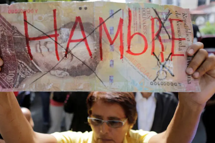
	Venezuela: manifestante segura cartaz de notas de dinheiro escrito &#39;Fome&quot;, dia 25/05/2016
 (Marco Bello / Reuters)