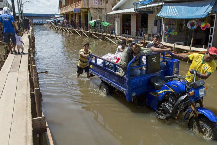 
	Moradores puxam uma moto pela cidade de Tabatinga, inundada pelas enchentes do Rio Solim&otilde;es, no estado do Amazonas
 (REUTERS/Bruno Kelly)