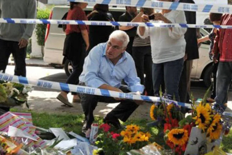 Mitch Winehouse observa as flores deixadas pelos fãs em homenagem à filha: 'sinto que preciso escrever este livro para contar a verdadeira história dela e poder me recuperar' (Ben Stansall/AFP)
