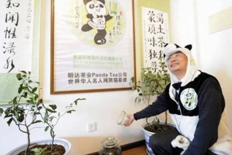 O empresário An Yanshi, fantasiado, mostra um pote contendo fezes de panda usadas como adubo para um chá especial (Liu Jin/AFP)