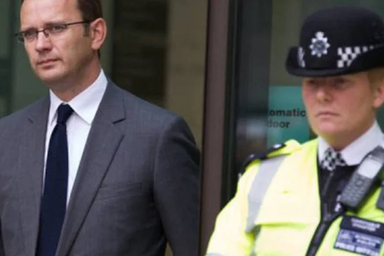 
	Andy Coulson, acompanhado por um policial, deixa a audi&ecirc;ncia: o ex-assessor do premi&ecirc; brit&acirc;nico David Cameron &eacute; um dos indiciados
 (Andrew Cowie/AFP)