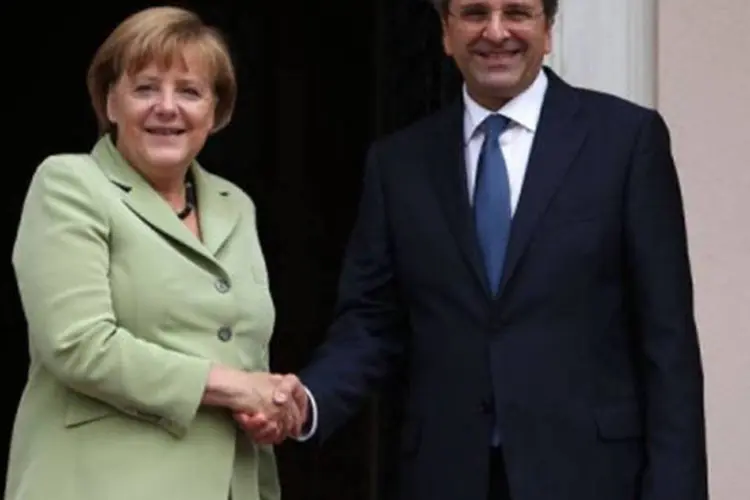 A chanceler alemã, Angela Merkel e o primeiro-ministro grego, Antonis Samaras: a Grécia deve votar novas medidas fiscais, disse a mesma fonte (©AFP / Thanassis Stavrakis)