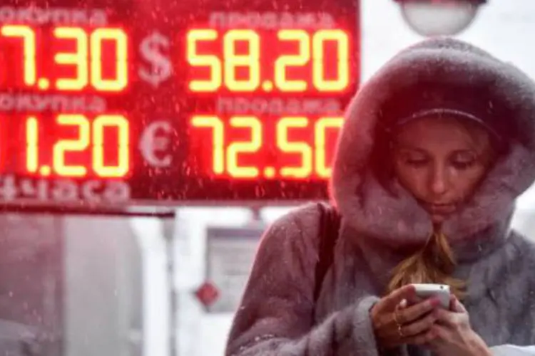 
	Mulher passa por uma placa de an&uacute;ncio com taxas de moeda estrangeira e o rublo em Moscou
 (Kirill Kudryavtsev/AFP)