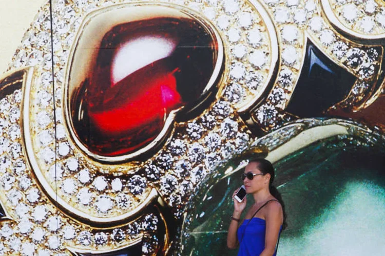 Mulher caminha na frente de anúncio de loja de jóias em Beverly Hills, EUA (Patrick Fallon/Bloomberg)