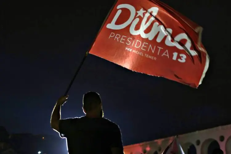 
	Um apoiador do PT segura bandeira com o nome de Dilma: os tucanos alegam que as duas pe&ccedil;as estimulam o &oacute;dio, o preconceito e a divis&atilde;o de classes
 (REUTERS/Pilar Olivares)