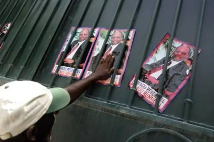 Partidário do ex-presidente haitiano Jean Bertrand Aristide coloca cartazes de apoio do lado de fora de sua casa (Hector Retamal/AFP)