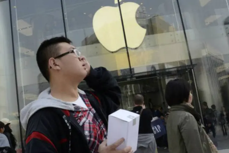 Cliente segura produto da Apple em frente à nova loja da empresa em Pequim, na China (©afp.com / Wang Zhao)
