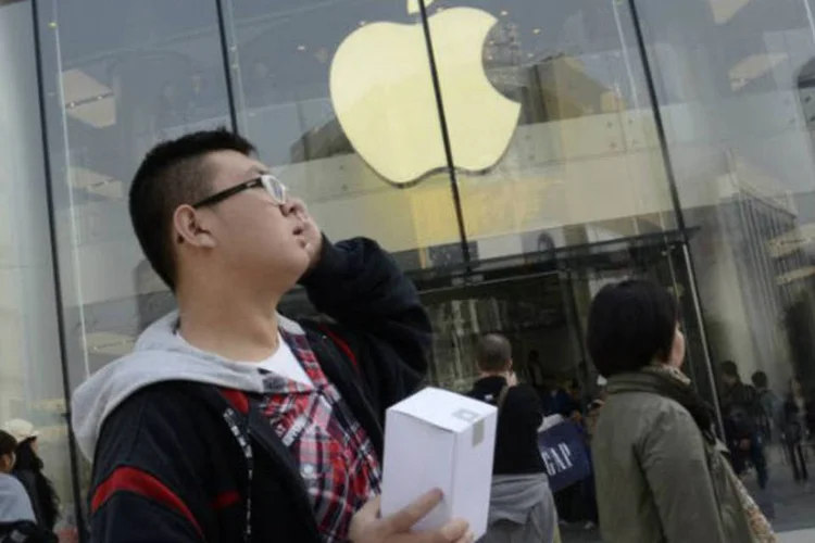 Cliente segura produto da Apple em frente à nova loja da empresa em Pequim, na China (©afp.com / Wang Zhao)