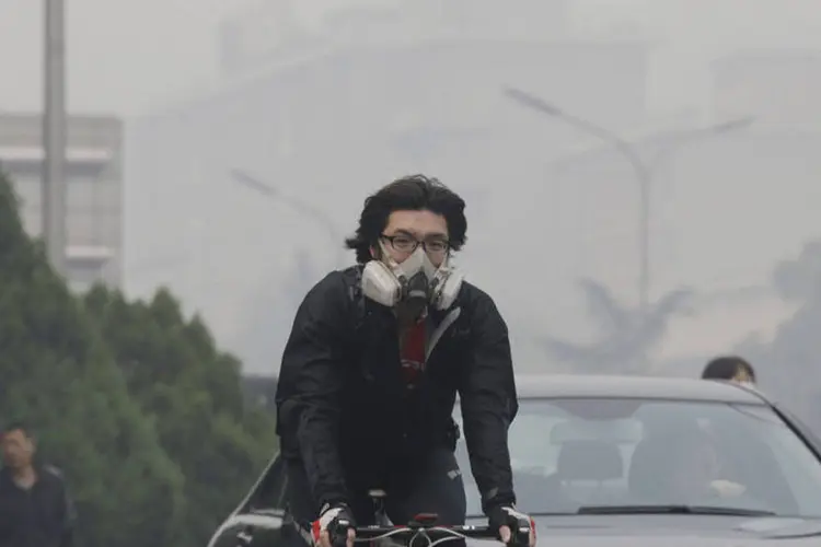Ciclista com máscara contra poluição roda pelas ruas de Pequim (REUTERS/Reuters)
