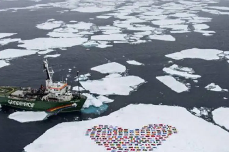Tripulação do navio My Arctic Sunrise desenham um coração com as bandeiras de 193 países-membros da ONU em uma placa de gelo flutuante ao norte do Círculo Polar Ártico
 (Danile Beltra/AFP)