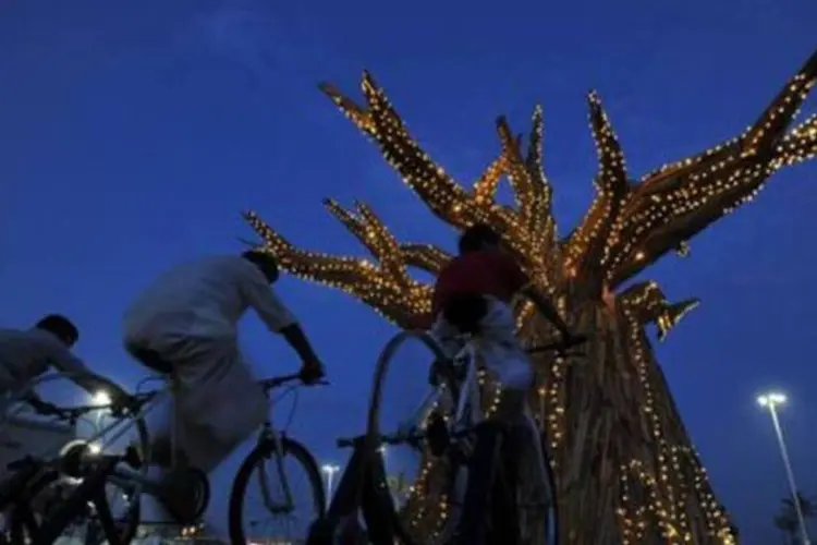 Sul-africanos passam por baobá enfeitado com luzes alimentadas com energia renovável em Durban (Alexander Joe/AFP)