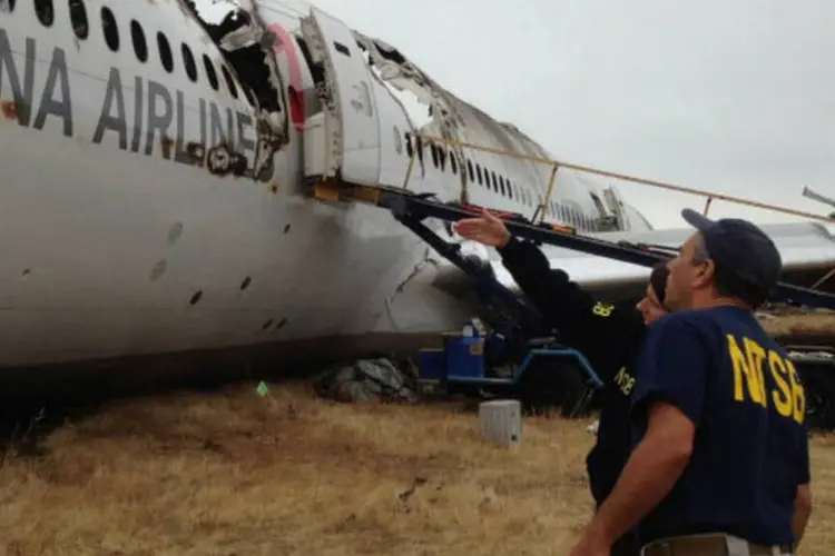 Investigadores conversam próximo dos destroços do avião Boeing 777 da Asiana Airlines após acidente no aeroporto de San Francisco, na Califórnia (NTSB/Divulgação via Reuters)