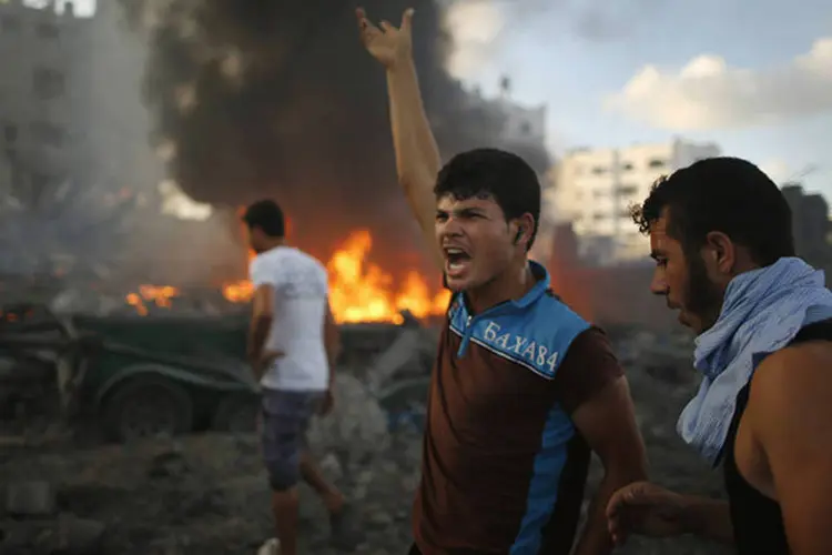 
	Palestinos no local de um ataque a&eacute;reo de Israel, na Cidade de Gaza
 (Mohammed Salem/Reuters)