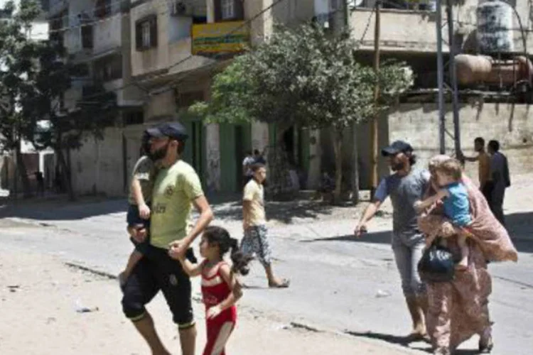 
	Uma fam&iacute;lia palestina foge de um pr&eacute;dio localizado no mesmo bloco de outro pr&eacute;dio que foi atingido por um m&iacute;ssil israelense
 (AFP)
