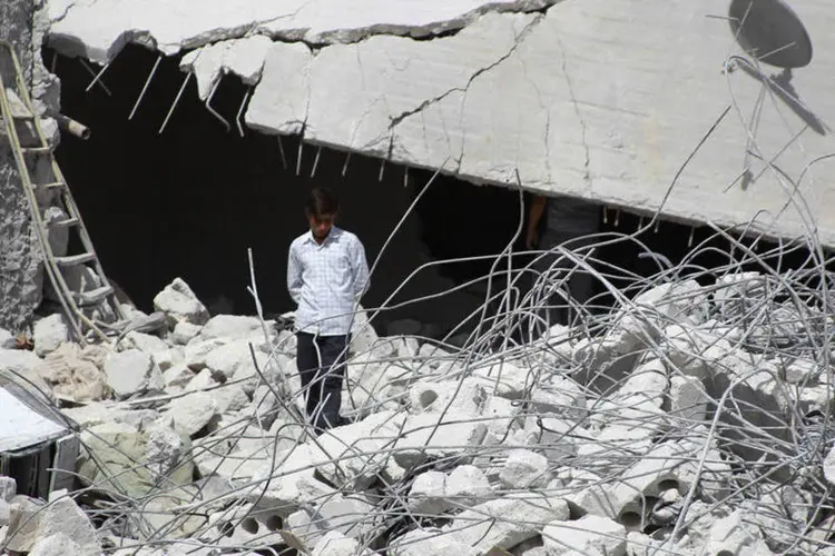 Morador caminha sobre destroços de prédio destruído por ataque aéreo dos EUA em Idlib, na Síria (Ammar Abdullah/Reuters)