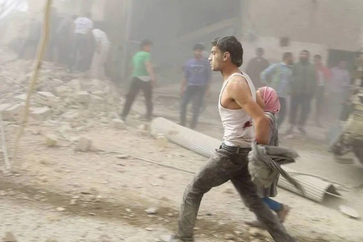 Sobreviventes do ataque aéreo, que os ativistas dizem ter sido das forças de Assad, correm do distrito de al-Shaar, em Alepo, Síria (Ahmad Othman/Reuters)