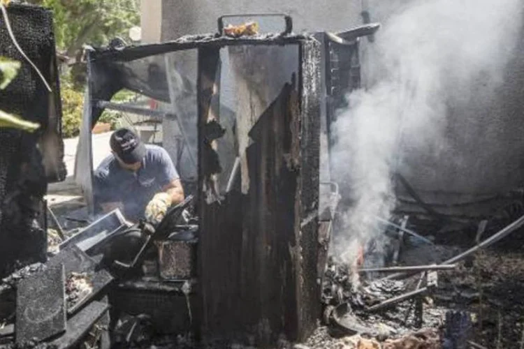 Especialista apaga um incêndio provocado pela queda de um foguete palestino em Kfar Aza (Jack Guez/AFP)