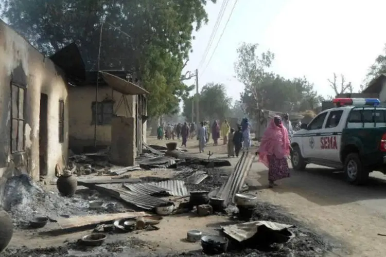 
	Nig&eacute;ria: Pessoas passam por casas queimadas em ataque do Boko Haram, em janeiro
 (AFP)
