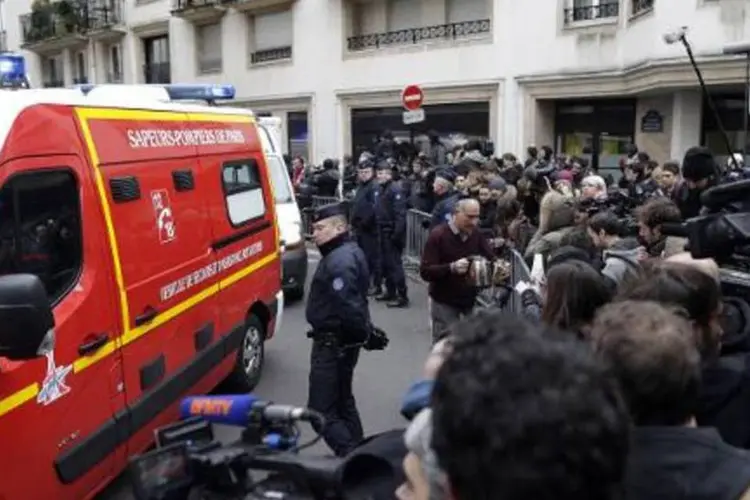 Bombeiros e policiais cercados por jornalistas em frente à sede da revista Charlie Hebdo, em Paris (Kenzo Tribouillard/AFP)