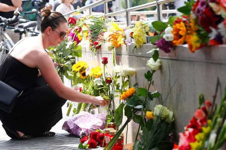 Mulher coloca flores em frente a shopping Olympia, em Munique, onde ocorreu o ataque (Arnd Wiegmann/Reuters)